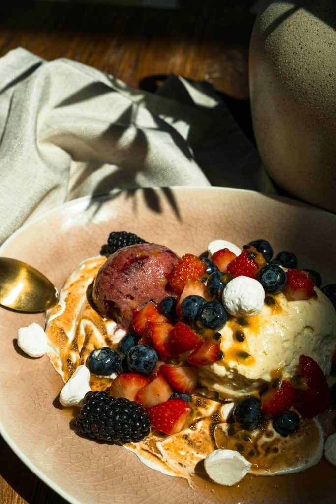 pexels-photo-8112924-8112924 A close-up of a delicious ice cream dessert topped with fresh berries and drizzle.